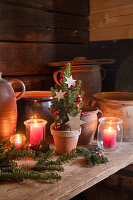 Rustikale Weihnachtstischdekoration mit Mini-Weihnachtsbaum, Kerzen und Tannenzweigen