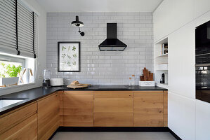 Modern kitchen with wooden elements and white tiled wall in Stegny, Warsaw