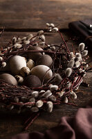 Easter nest made of pussy willows with eggs on a wooden table