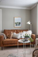 Brown leather sofa with cat and side table with candles and plant in the living room