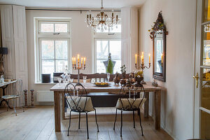 Dining room with wooden table and wrought-iron chairs, candlesticks and chandelier