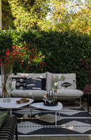 Modern patio with white sofa, patterned cushions, outdoor rug and coffee tables