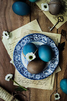 Easter eggs in shades of blue on blue patterned vintage plate and old letters