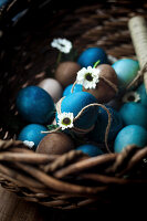 Easter eggs in shades of blue and natural colors in a rustic basket