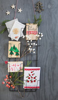 Weihnachtliche Karten und Dekoration an Wandgitter, dekoriert mit Tannenzweigen