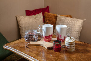 Teetassen und Tee in Einweckglas auf antikem Holztisch
