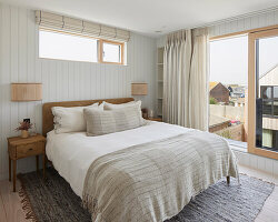 Schlafzimmer mit Holzelementen und Bettwäsche in Naturtönen