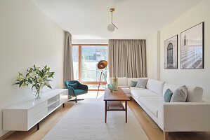 Hell eingerichtetes Wohnzimmer mit weißem Sofa und modernen Leuchten