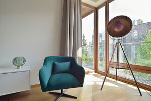 Modern living room with dark teal velvet armchair and tripod floor lamp