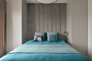 Modernes Schlafzimmer mit Betonwand und blauer Bettwäsche