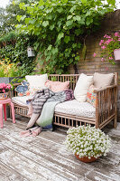 Outdoor sofa with cushions and blankets on patio, wall and plants