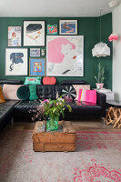 Living room with black leather sofa, colourful wall art and green accent wall