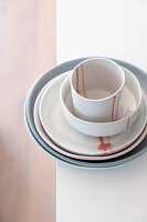 Stacked ceramic crockery on a light-coloured surface with red colour accents