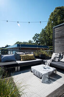 Modern roof terrace with grey lounge furniture, fairy lights and coffee table