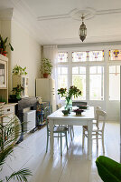 Dining room with white wooden furniture, plants and large window front