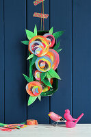 DIY flower decoration made from painted cardboard in front of a blue wall
