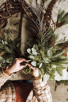 Ein DIY-Weihnachtskranz wird aus Zweigen, Eukalyptus und Zapfen gebunden