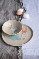 Ceramic plate and bowl with bunny motifs on linen cloth
