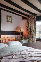 Country-style bedroom with wooden beamed ceiling and floral curtains