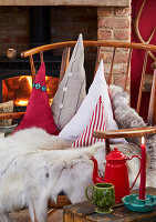 Cosy corner with decorative cushions in front of a fire and wooden chair