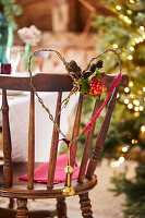 Heart-shaped wreath with cones and berries on a wooden chair