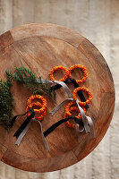 Craft project: decoration made from tangerine peels with bows and twigs on a wooden table