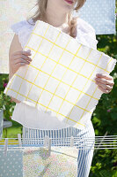 Woman hangs chequered oilcloth on washing line to dry
