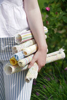 Woman carrying colourful fabric rolls in the garden