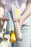Woman holding fabric rolls with different patterns