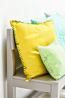 Yellow and green DIY cushions on a grey wooden bench