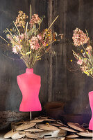 Pink-coloured dressmaker's dummy with dried flowers in a rustic setting