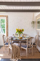 Dining room with round table, sunflowers and light-coloured wooden chairs with upholstery