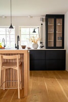 Kitchen with kitchen island in light-coloured wood and black cabinets
