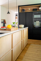 Modern kitchen with kitchen island in light-coloured wood and black fitted cupboards