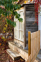 Rustikales Holzhaus mit Veranda im herbstlichen Garten