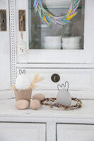 Easter decorations on a vintage kitchen buffet: wooden eggs, bunny figurines made of concrete and wire and a wreath made of willow catkins
