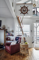 Sailor flair in the living room with red leather armchair, rattan table and wooden steering wheel