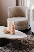 Round armchair in bouclé fabric next to coffee table with marble candles