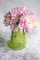 Chrysanthemums (Chrysanthemum) in green glass vase on stone table