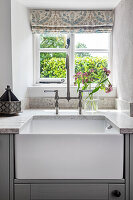 Rustic kitchen with white ceramic sink and fabric blinds