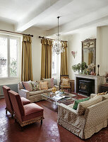 Wohnzimmer mit Kamin, kristallener Deckenleuchte und gemusterten Sofas