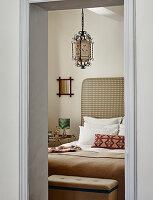 Schlafzimmer mit gemustertem Kopfteilelement und orientalischer Hängelampe