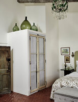 Schrank mit Glastüren und Kronleuchter im Schlafzimmer mit Fliesenboden