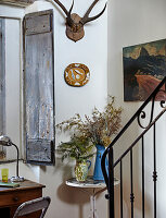 Wohnecke mit antikem Fensterladen und Blumenarrangement auf Beistelltisch