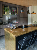 Modern kitchen with brass-coloured kitchen island and black and gold pendant lights