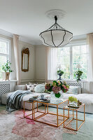 Cream-coloured corner sofa and coffee tables in a copper-coloured look in the light-flooded living room