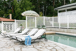 Pool area with white sun loungers and parasol on a stone terrace