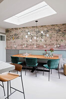 Essbereich mit Holztisch, grünen Samtstühlen, Bank, Kronleuchter und Kranich-Tapete, Oberlicht