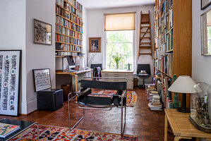 Wohnzimmer mit deckenhohen Bücherregalen und Lederstuhl