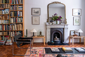 Klassisches Wohnzimmer mit Marmorkamin und Bücherwand, gemusterter Teppich